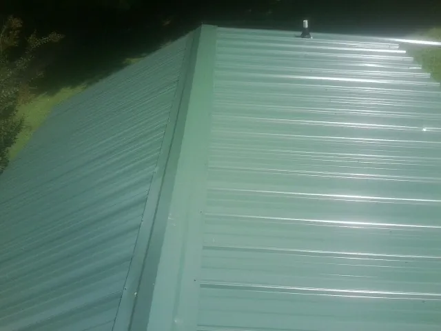 New green metal panels meeting at the ridge of a roof — Flat Roof Repair work by our crew in Brownsville