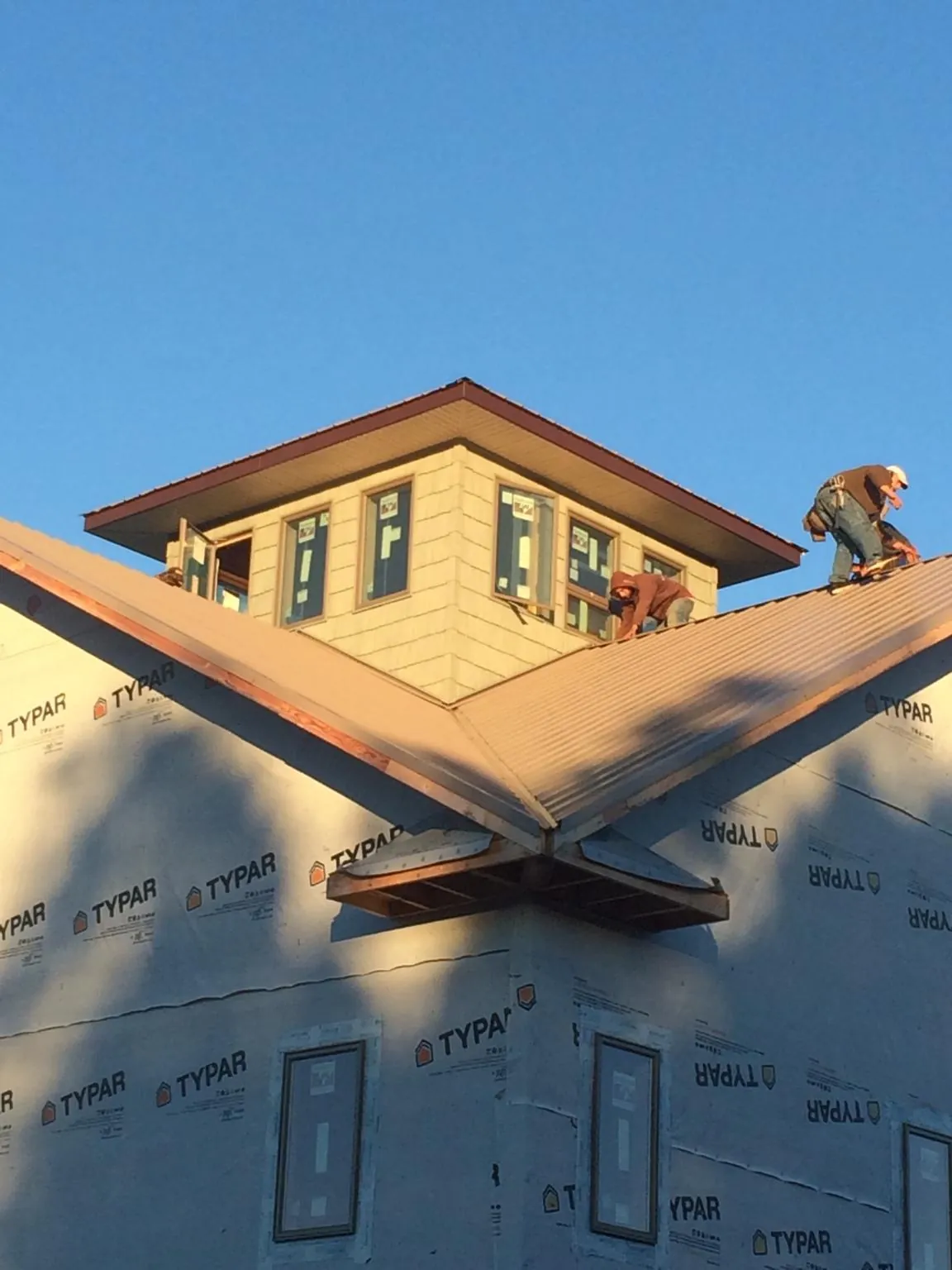Roofers working around a rooftop cupola on a new metal roof at sunset — Roof Waterproofing in Brownsville by Roofing Brothers